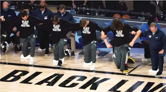  ?? ASHLEY LANDIS/AP PHOTOS ?? Members of the Milwaukee Bucks join arms as they kneel during the National Anthem before a game Aug. 29.