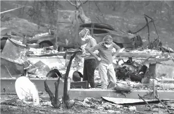  ?? ASSOCIATED PRESS ?? Two women, sort through the rubble of the property on 106 West Gate Drive in Napa, California.