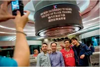  ?? — AFP ?? Traders and guests pose for photos at an event to celebrate the end of floor trading at the Hong Kong Stock Exchange on Friday. Veteran deal-makers in Hong Kong donned their distinctiv­e red vests for the last time as the city’s historic trading hall closed for business for the final time.