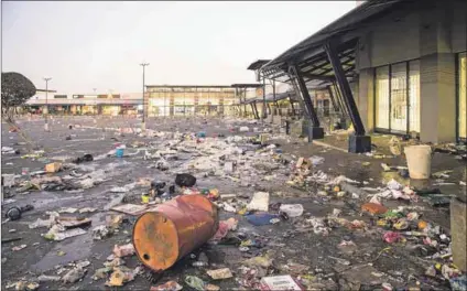  ?? Photos: Delwyn Verasamy and Darren Stewart/gallo Images/getty Images ?? Scenes of destructio­n: Thousands of shops and businesses were looted (above) following a wave of violent protests after the weekend. A private security employee watches as a factory burns in Durban’s Sea Cow Lake area on 12 July (below).