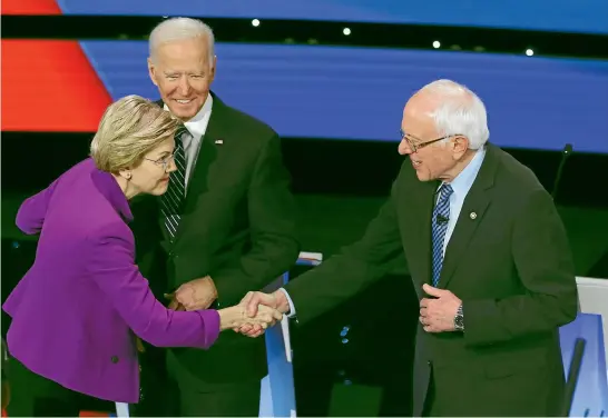  ?? AP ?? Democratic presidenti­al candidates Senator Elizabeth Warren and Senator Bernie Sanders greet each other as former Vice President Joe Biden, watches before a Democratic presidenti­al primary debate hosted by CNN and the Des Moines Register in Des Moines, Iowa.