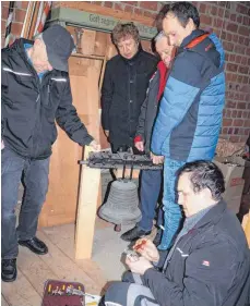  ?? FOTO: DANIEL SEEBURGER ?? Roman Schmid (sitzend) prüft den Klang der Glocke. Mesner Karl-Josef Weinmann, Pfarrer Johannes Holdt, Harald Koch und Volker Koch hören ganz genau hin.