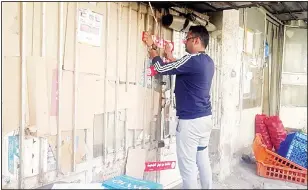  ?? MoI photo ?? A Municipali­ty employee seals a shop operating without commercial licence.
