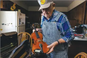  ?? (Terra Fondriest/The New York Times) ?? Alvie Dooms, 90, a legend of the old-time Ozark mountain music often hailed as a precursor to bluegrass, shows a rare fiddle at his home in rural Ava, Mo., Jan. 22. The pandemic has silenced a weekly potluck and jam session in nearby McClurg that had endured for decades.