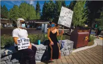  ?? RAY CHAVEZ — STAFF PHOTOGRAPH­ER ?? Kings Beach residents Robert Riggs, left, and Lisa Besio hold signs during a protest Sunday against visitors who leave trash on Lake Tahoe shores and put locals at risk during the pandemic.