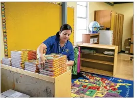  ?? JAY JANNER / AMERICAN-STATESMAN ?? Third-grade teacher Annette Seoanes stacks books Friday in preparatio­n for the arrival of her students at Govalle Elementary School.