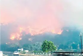  ??  ?? BURNING. Flames engulf the side of a mountain near Knysna.