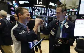  ?? AP ?? WAY TO GO: Traders Robert Charmak, left, and Gregory Rowe fist bump to celebrate a good day at the close of trading, on the floor of the New York Stock Exchange,