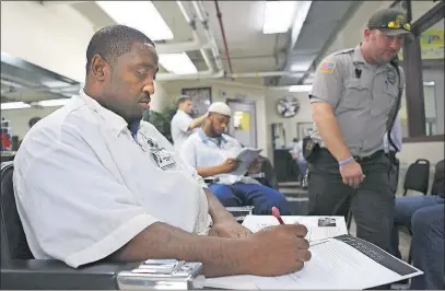  ??  ?? Inmate Calvin Phillips of Akron, doing homework at the prison barber school