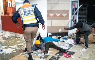  ?? EMMANUEL CROSET / AFP ?? Um homem bate com uma barra de ferro em outro caído no chão de um shopping em Soweto