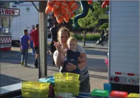  ??  ?? Kortnie Lynch, 36, helps 1-year-old Emerson Lynch toss Ping Pong balls into fish bowls June 13 as part of the opening night of the St. Joseph Parish and School Carnival and Music Festival. The festival is running from 6 to 10 p.m. each day until June 16.