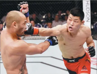  ?? BRANDON MAGNUS / ZUFFA LLC VIA GETTY IMAGES ?? China’s Li Jingliang lands a straight right to Frank Camacho’s face during their welterweig­ht bout at UFC Fight Night in Singapore in June. Li, a native of Xinjiang who fights out of Beijing, has a pro MMA record of 13-4.