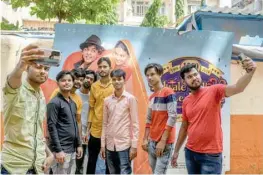  ?? ?? People take selfies with a movie poster for Dilwale Dulhania Le Jayenge at the Maratha Mandir cinema in Mumbai.