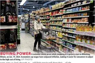  ?? AP PHOTO ?? BUYING POWER
A customer checks prices while shopping at a grocery store in Wheeling, Illinois, on Jan. 19, 2024. Economists say wages have outpaced inflation, making it easier for consumers to adjust to the high cost of living.