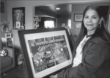  ?? Raul Roa Los Angeles Times ?? ANA ROLDÁN, mother of USA Soccer player Cristian Roldán, shows a photo of her son’s high school championsh­ip team at her Pico Rivera home. Cristian scored 54 goals for El Rancho High in the 2012-2013 season.