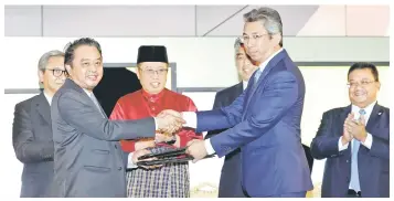  ?? — Photo by Chimon Upon ?? Abdul Aziz (left) and Shamsairi exchange the signed documents in the presence of Abang Johari (third left) and others.