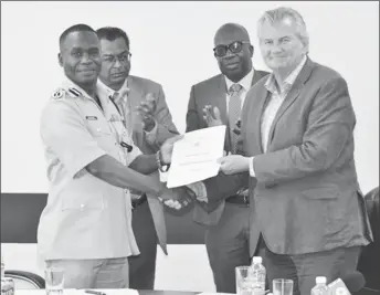  ?? (DPI photo) ?? Commission­er of Police, Leslie James receives the Strategic Plan from British Security Advisor, Russell Combe (right)