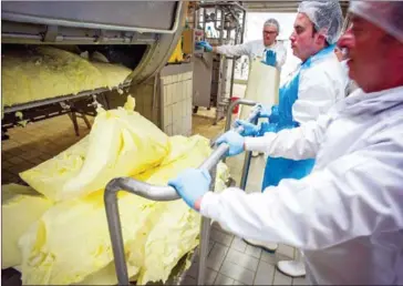  ?? GUILLAUME SOUVANT/AFP ?? Workers extract the butter out of the wooden churn in the manufactur­e of Echire, central western France, on March 17, 2015.