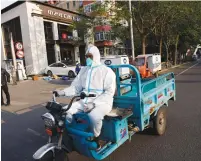  ?? (Carlos Garcia Rawlins/Reuters) ?? A WORKER IN a protective suit drives past an area under corona lockdown in Beijing yesterday.