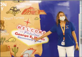  ??  ?? Principal Margarita Harris points to an altered “Welcome to Fabulous Las Vegas” sign on a mural inside the new school building.