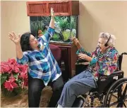  ??  ?? Nancy Lyles, Treemont Health Care Center’s activity director and coordinato­r of the Music and Memory program, engages with resident Isabelle, who clearly enjoys her gospel music, which has a positive impact on her demeanor.