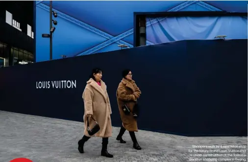  ?? ?? Shoppers walk by a new retail shop for the luxury brand Louis Vuitton that is under constructi­on at the Taikoo Li Sanlitun shopping complex in Beijing.