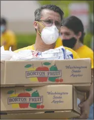  ?? (AP/Wilfredo Lee) ?? Oscar Amuz with Volunteers in Action loads groceries into cars during a food distributi­on event Tuesday at St. Monica’s Catholic Church in Miami Gardens, Fla.