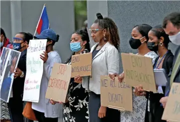  ?? MATT sTONE PHOTOs / HErALd sTAFF ?? FOR HAITI: Community leaders holding signs bow their heads out of respect.