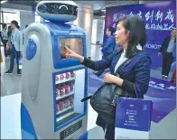  ?? ZHU YUANBIN / FOR CHINA DAILY ?? A woman interacts with a smart Magic Wand vendor in Guangzhou.