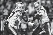  ?? Adrian Kraus / Associated Press ?? Patriots quarterbac­k Mac Jones, right, completes a handoff to Damien Harris, a play run nearly every time against the Bills.