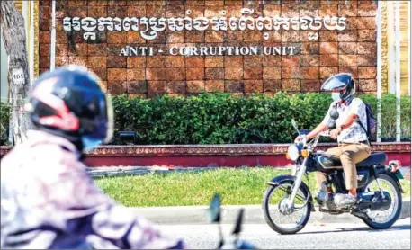  ?? HONG MENEA ?? Motorcycli­sts ride past the Anti-Corruption Unit headquarte­rs in Phnom Penh.