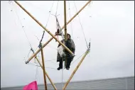  ?? (AP/PA/Yui Mok) ?? An animal rights protester sits suspended from a bamboo structure Saturday outside a McDonald’s distributi­on site in Hemel Hempstead, England.