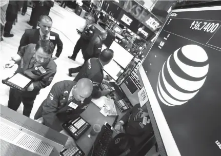  ?? Associated Press file photo ?? ABOVE: Traders gather on May 19, 2014, at the post that handles AT&T on the floor of the New York Stock Exchange. AT&T says the market for its new internet cable service, DirecTV Now, could be as large as 20 million households.