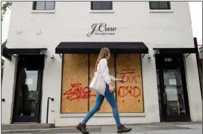  ?? (AP/Andrew Harnik) ?? A woman walks past a boarded-up J. Crew storefront in Washington last week.