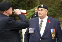  ??  ?? Below left: Murray Northrup’s nephews, Canadian veterans Jim Northrup, left, and Mark Northrup, right, share a drink of Canadian maple whisky during a rededicati­on ceremony for their uncle’s gravestone. During the ceremony, the men also poured whisky on their uncle’s grave.