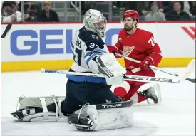  ?? PHOTOS BY PAUL SANCYA — THE ASSOCIATED PRESS ?? Winnipeg Jets goaltender Connor Hellebuyck (37) deflects a Detroit Red Wings center Dylan Larkin (71) shot in the second period of Thursday’s game in Detroit.