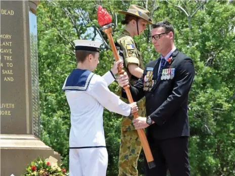  ?? Photos: Bev Lacey ?? IMPORTANT MOMENT: Toowoomba ex-serviceman community member Brad Donald passes the torch to Navy cadet leading seaman Zac Picker at the Mothers’ Memorial Remembranc­e Day service.