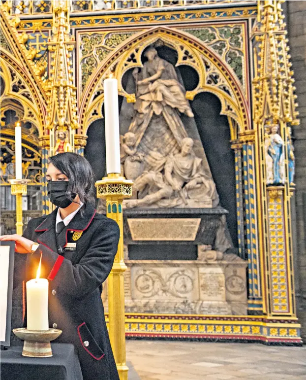  ??  ?? Rosa Wlodarczyk adjusts a photograph of the Duke displayed alongside the nave at Westminste­r Abbey, which has been dressed in black to mark his death