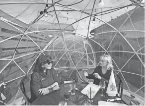  ?? PHIL MASTURZO/AKRON BEACON JOURNAL ?? Dorie Beltram, left, and Linda Olds converse as they wait for other friends to arrive for a Christmas gathering inside one of the three outdoor igloos at Darby’s on Dec. 17, 2021, in Cuyahoga Falls.