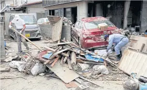  ??  ?? Local residents try to clear mud and debris in Mabi town in Kurashiki, Okayama Prefecture.