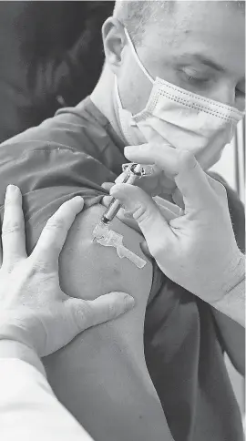  ?? JESSICA HILL/ AP ?? A health care worker gets the Pfizer- BioNTech vaccine.