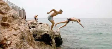  ?? Reuters ?? ↑
People dive into the sea from a rock during a heatwave in Alimos suburb, south of Athens, on Thursday.