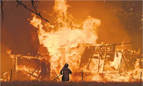  ??  ?? A firefighte­r tries to tackle the Gospers Mountain fire as a building burns in Bilpin, New South Wales