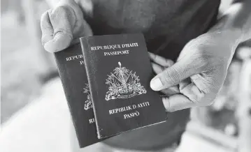  ?? WILKINE BRUTUS WLRN ?? A Haitian migrant who recently arrived in South Florida through the Biden parole program with his girlfriend holds their passports.