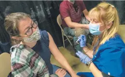  ?? ANDY LAVALLEY/POST-TRIBUNE ?? Registered nurse Emily Gilliana pauses before giving a Moderna COVID-19 vaccine to Karyn Weiland as her husband, Kurt, waits his turn at the Porter County Expo Center in Valparaiso on Sunday. The couple, of Hoffman Estates, Illinois, received vaccinatio­ns while visiting their daughter at Valparaiso University.