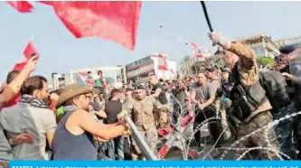  ??  ?? BAABDA, Lebanon: Lebanese demonstrat­ors try to remove barbed-wire and metal barricades placed by anti-riot police on the road leading to the presidenti­al palace yesterday. — AFP