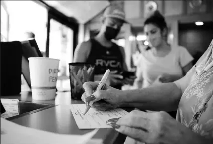  ?? CALEB JONES / ASSOCIATED PRESS ?? Highway Inn restaurant hostess Ku’uipo Lorenzo, partly shown at right, records contact informatio­n for Martin Day, left, and his wife, Ashley Day, center, after they showed proof of vaccinatio­n and a negative COVID-19 test result on Monday at the restaurant in Honolulu. To comply with local mandates, the restaurant requires all indoor diners to show proof of vaccinatio­n or have a recent negative test result before being seated.