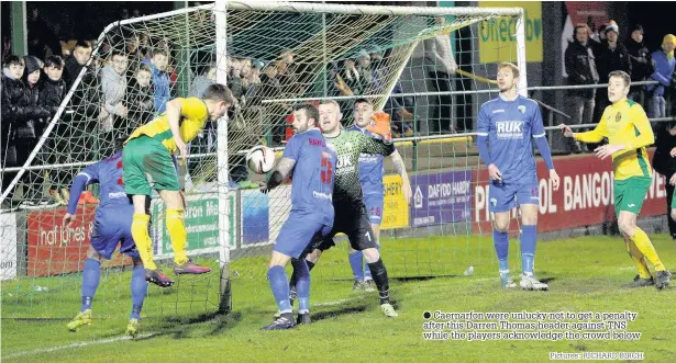  ??  ?? ● Caernarfon were unlucky not to get a penalty after this Darren Thomas header against TNS while the players acknowledg­e the crowd below