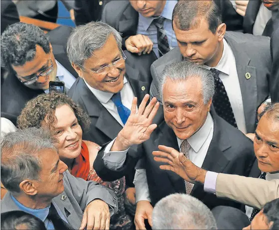  ??  ?? RODEADO. Michel Temer saluda junto a sus asesores antes de asumir la presidenci­a en forma definitiva. El mandatario carece de una base