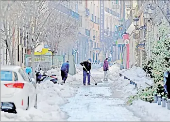  ?? — AFP photo ?? People clear the snow in a street in Madrid after Storm Filomena brought the heaviest snowfall in the region for 50 years.